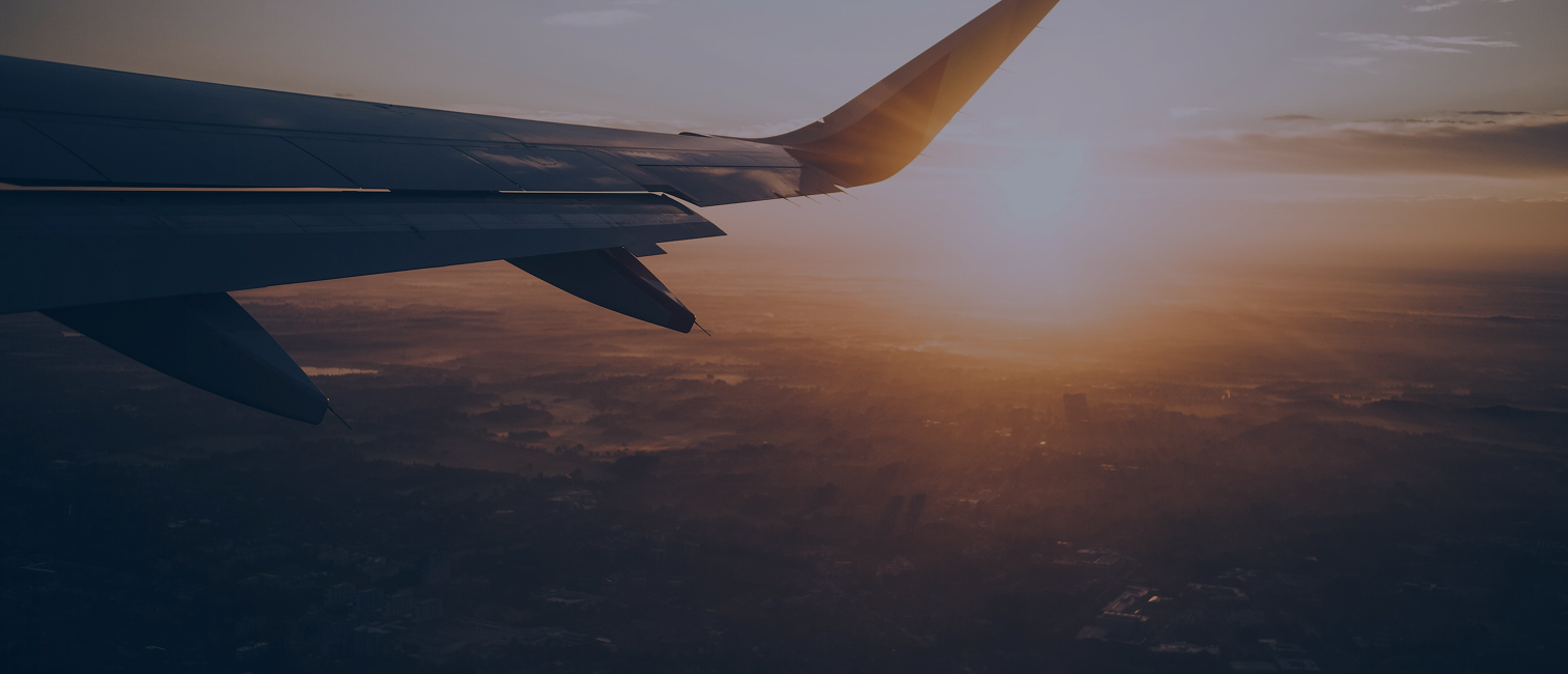 Bild på flygplansvinge i solnedgången, tagit inifrån flygplanet.