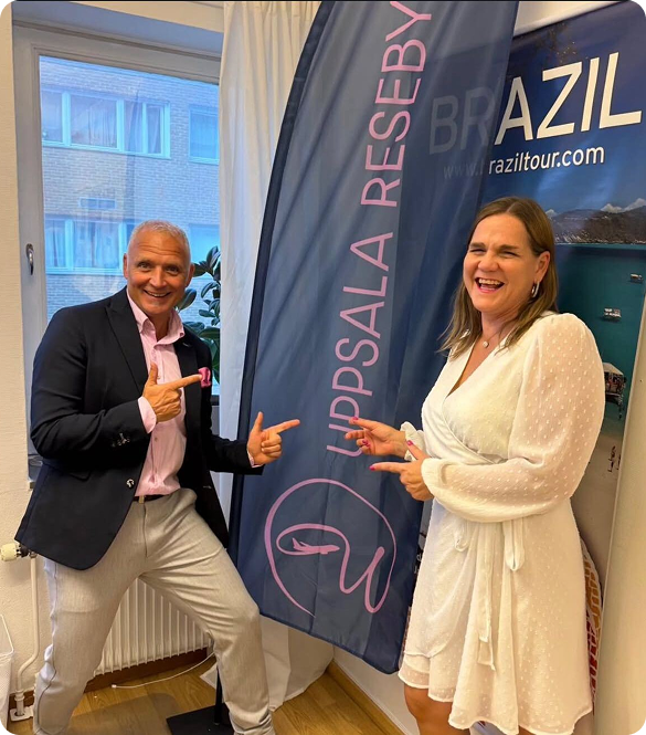 Niklas & Cecilia står och poserar med en banderoll från Uppsala Resbyrå