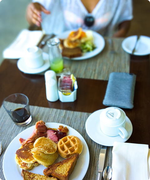 Bild på hotellfrukost med toast, våfflor, pannkakor och bacon.