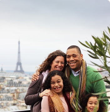 En familj poserar med utsikt över Paris och Eiffeltornet i bakgrunden