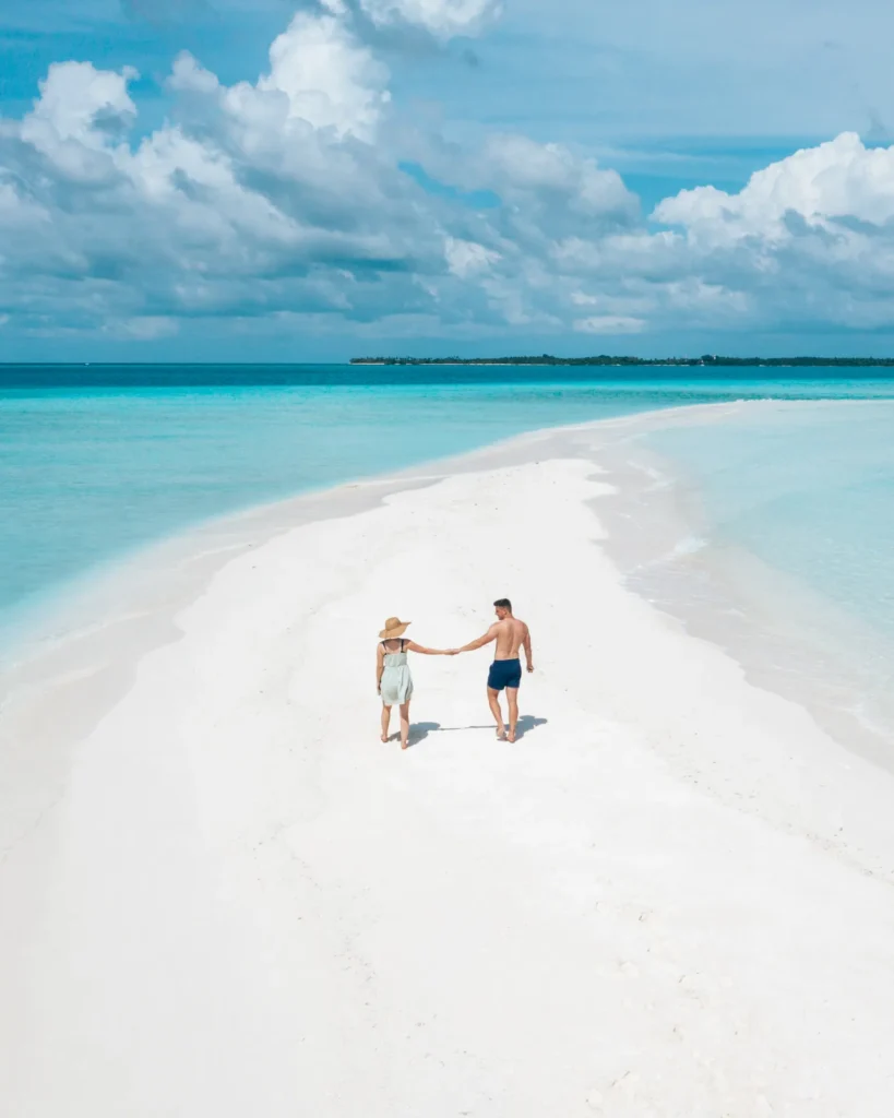 Par går hand i hand på en sandbank på Maldiverna